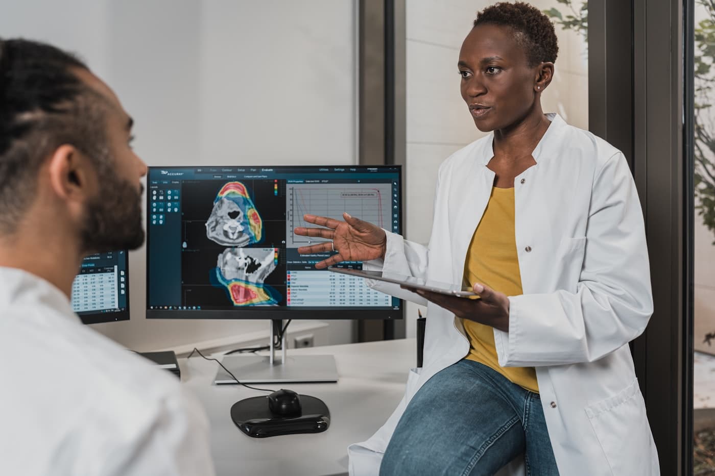 Dos profesionales de la salud analizan datos de un paciente en la pantalla de una computadora